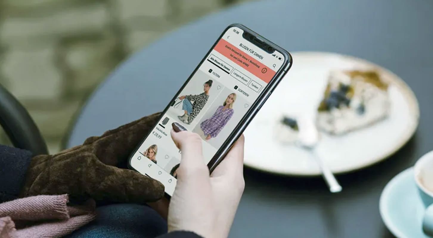 A person holding a smartphone displaying a bonprix shopping app interface.